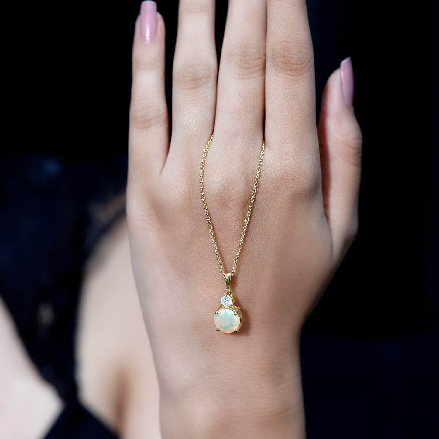 Gold necklace with a pendant on a hand against a dark background