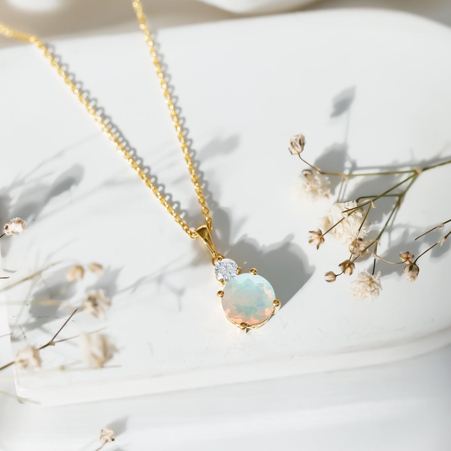 Opal necklace with gold chain on a white background with small flowers
