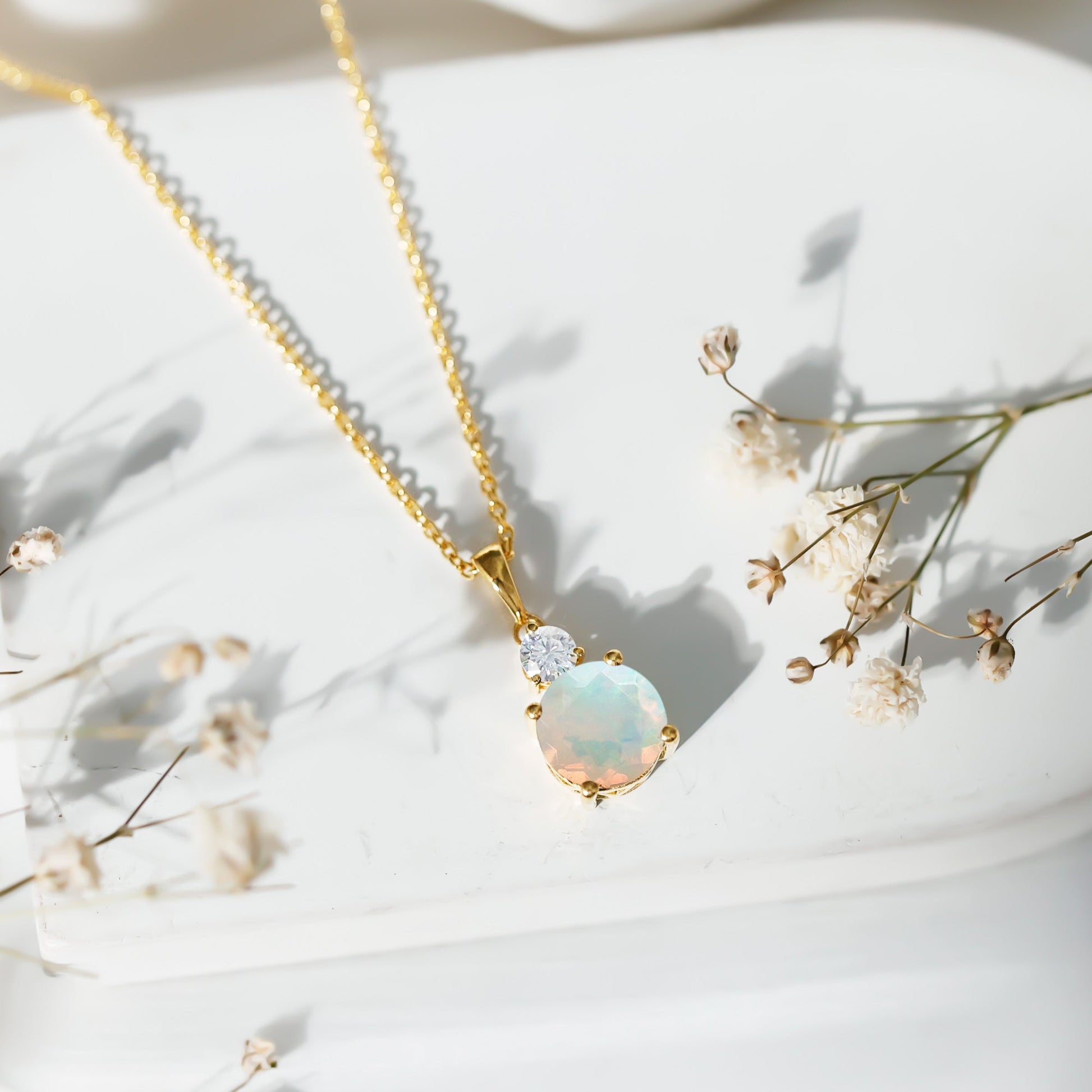 Opal necklace with gold chain on a white background with small flowers