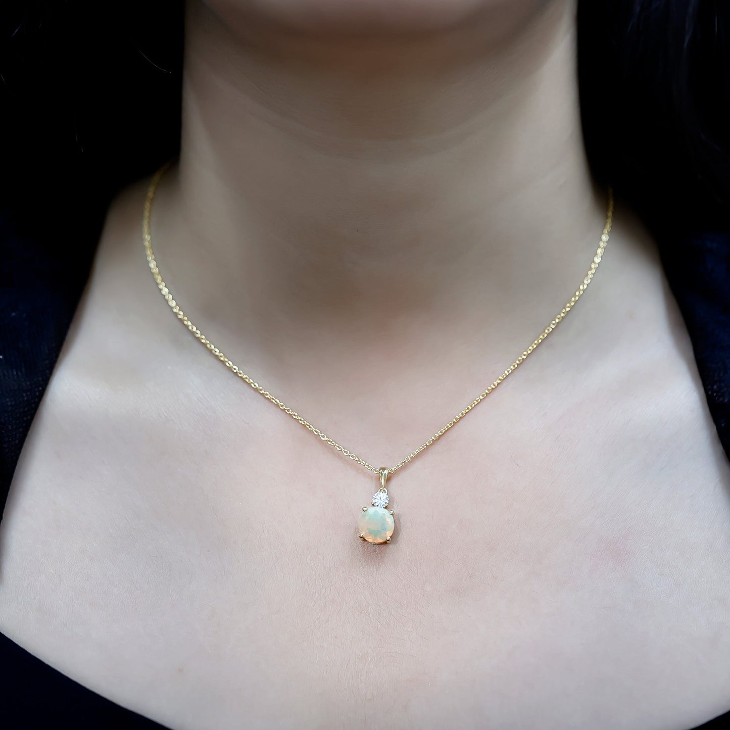 Gold necklace with a pendant on a person's neck against a dark background