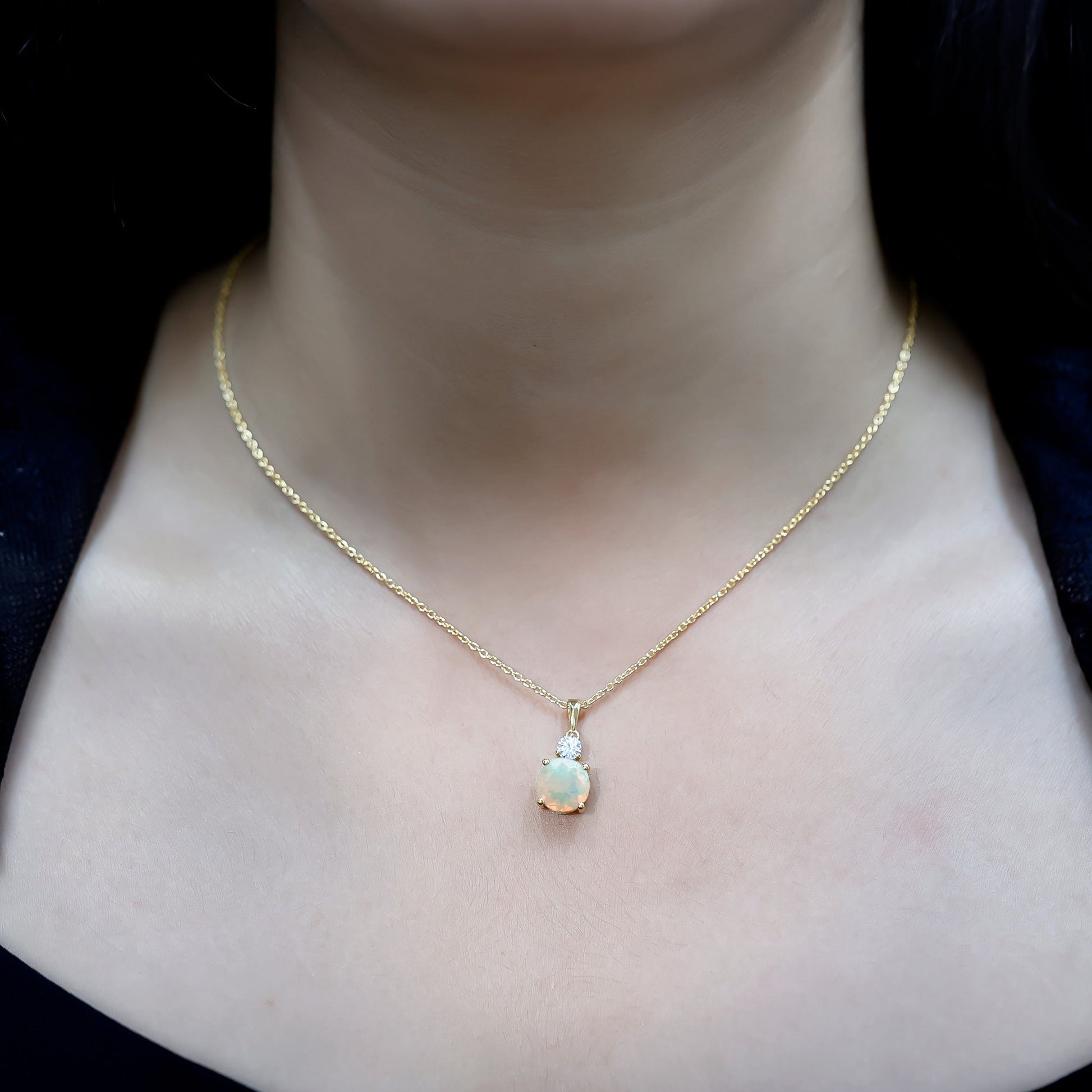 Gold necklace with a pendant on a person's neck against a dark background