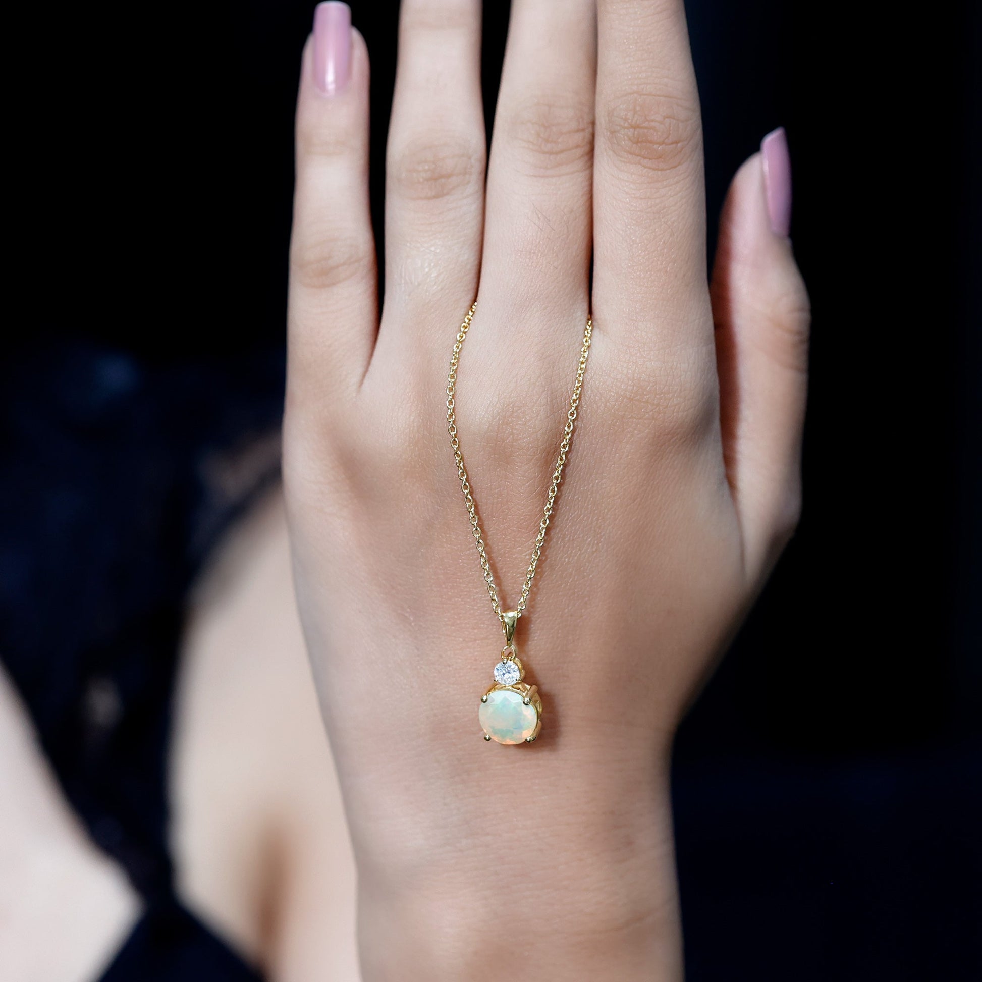 Gold necklace with a pendant on a hand against a dark background
